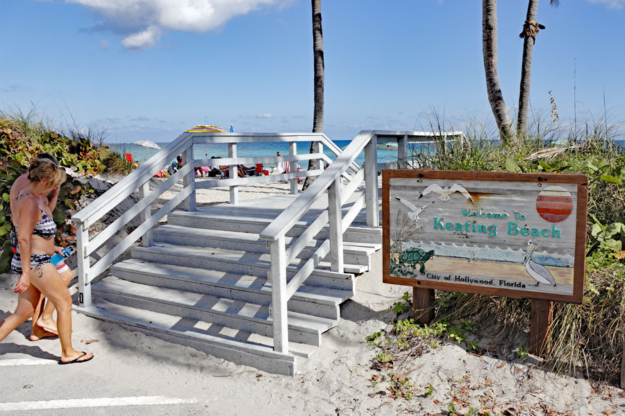  Welcome to Keating Beach sign with people walking up to the entrance stairs. People walking to and enjoying sunny Keating Beach. Hollywood, FL,  December 7, 2014.