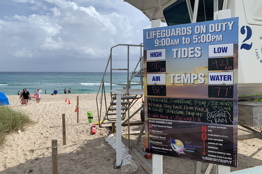 A sign showing lifeguards on duty from 9AM to 5PM in Lake Worth Beach. Water temperatures were 77 degrees  on this warm  January day in 2021.