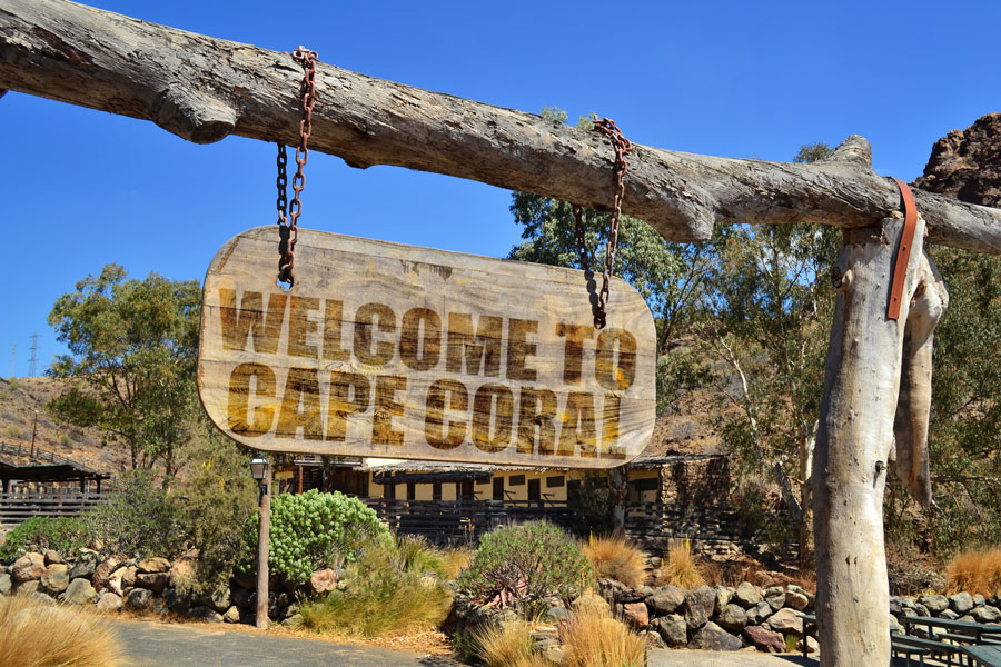 An old wood signboard with text "Welcome to Cape Coral" hanging on a branch. Photo credit ShutterStock.com, licensed.