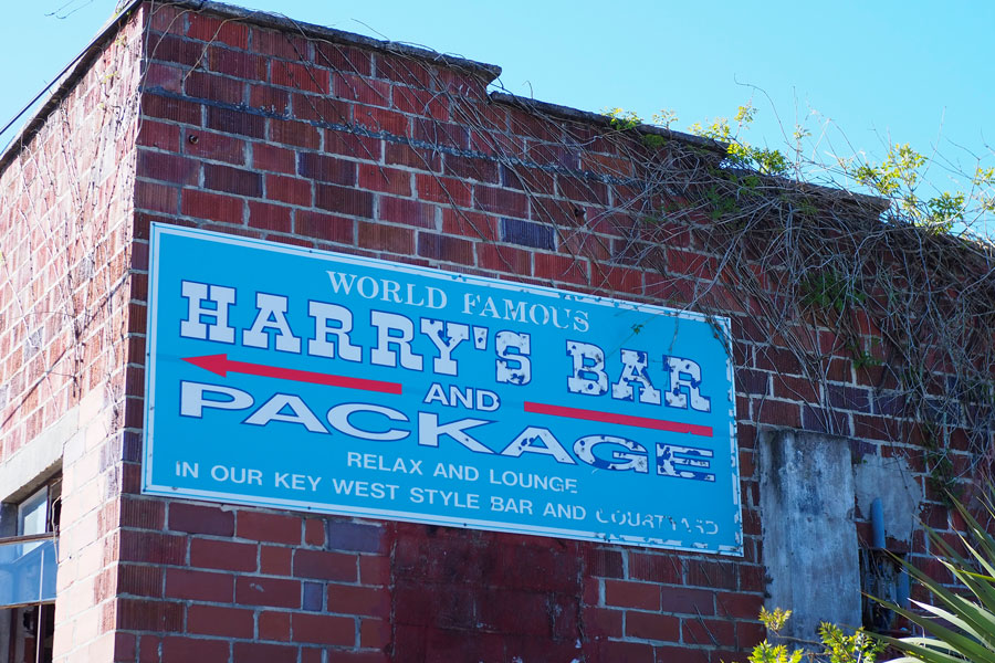 Sign and old brick wall for Harry's Bar in historic Carrabelle, Florida on March 23, 2019. Editorial credit: Ken Weaver / Shutterstock.com, licensed.