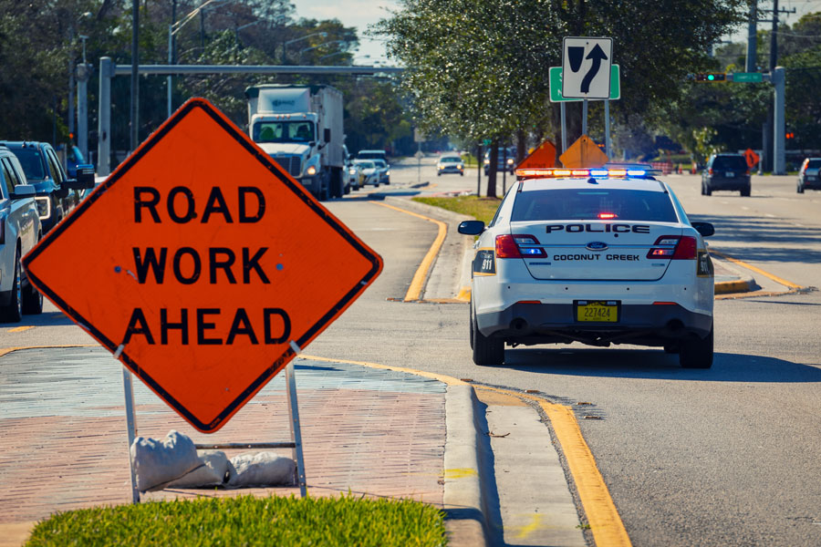 Police car staying on the road with lights for traffic control in road work zone. Coconut Creek, Florida, on February 05, 2021. Editorial credit: YES Market Media / Shutterstock.com, licensed.