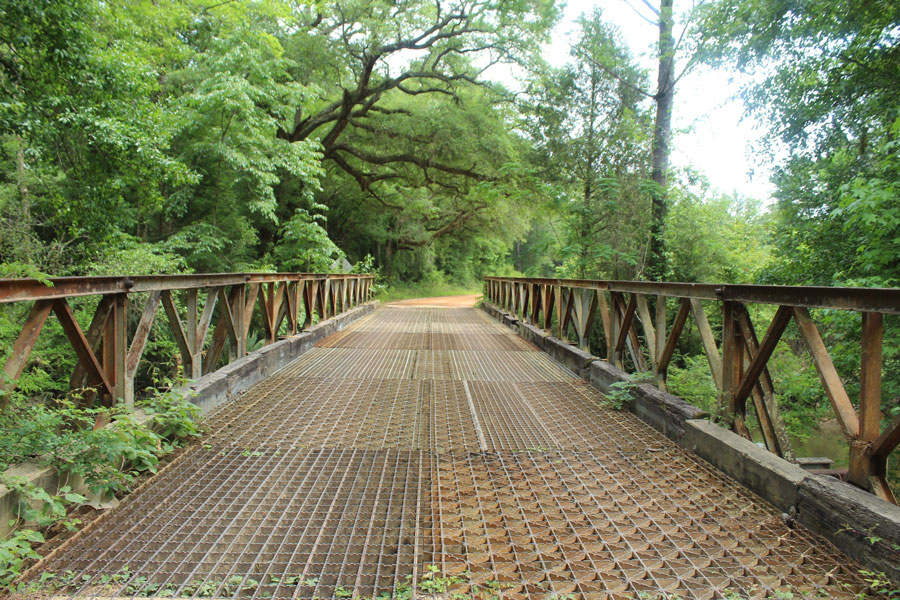 A rusty metal bridge leading to orange clay dirt road in Bonifay, Florida.