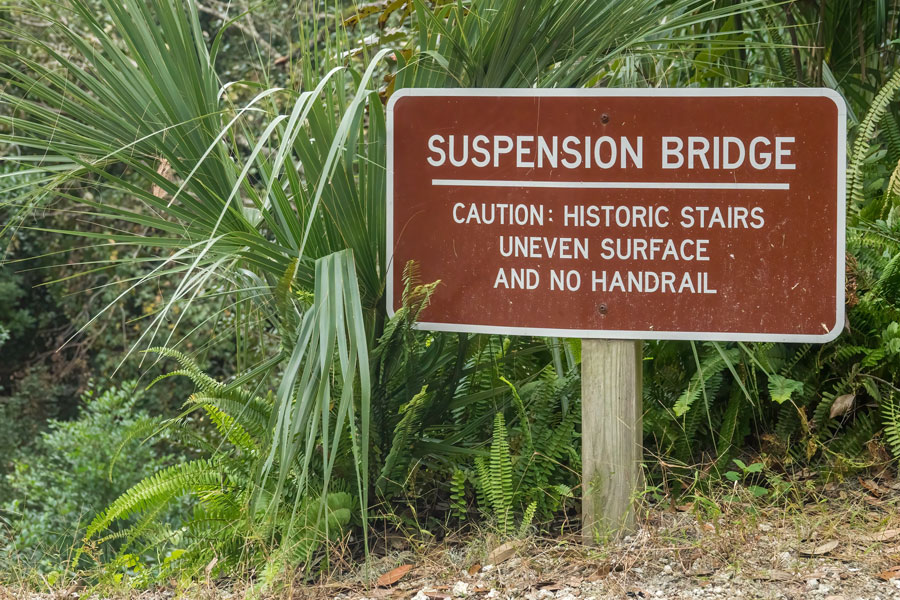  A roadside sign notifies hikers of risks in reaching a suspension bridge in historic Ravine Gardens State Park, built with federal funds in the 1930s and 1940s.