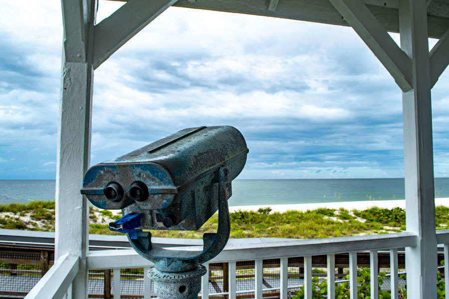 Binoculars watching the storm. Port Boca Grande Lighthouse and Museum stand strong on Gasparilla Island as a tropical storm with black clouds loom of the coast in the Gulf of Mexico